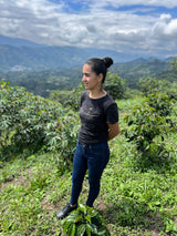 Woman standing in a coffee plantation with mountains in the background